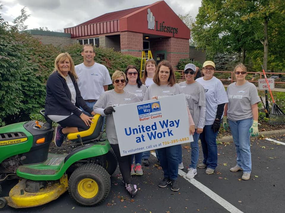 NexTier Bank employees helping clean up outside Lifesteps in Butler, PA holding a United Way at Work sign