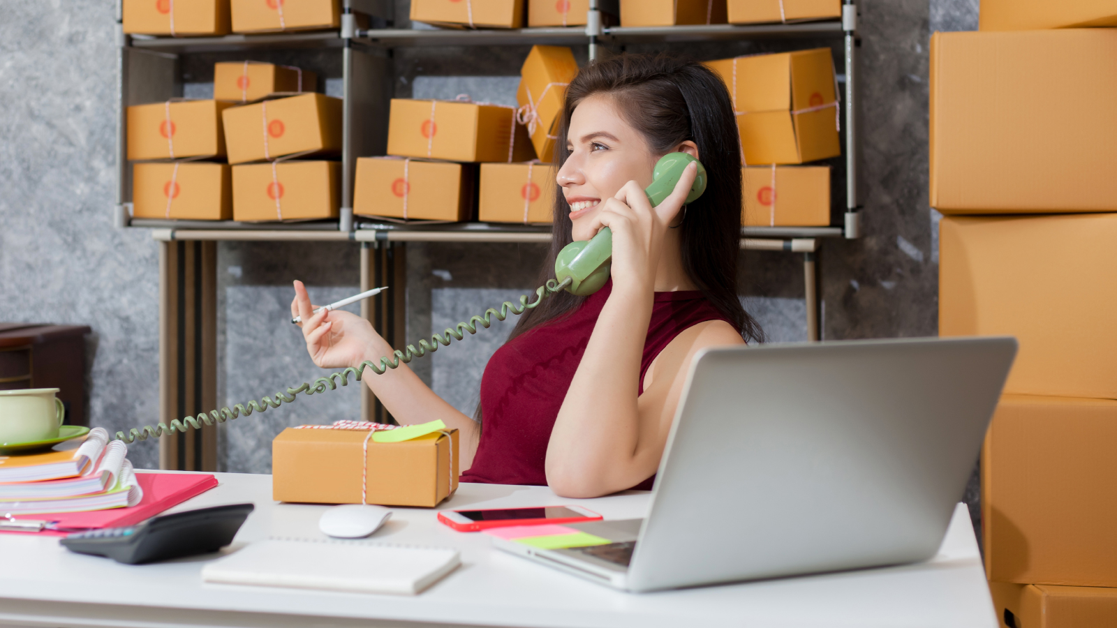 business woman on phone with shipping box and computer on desk