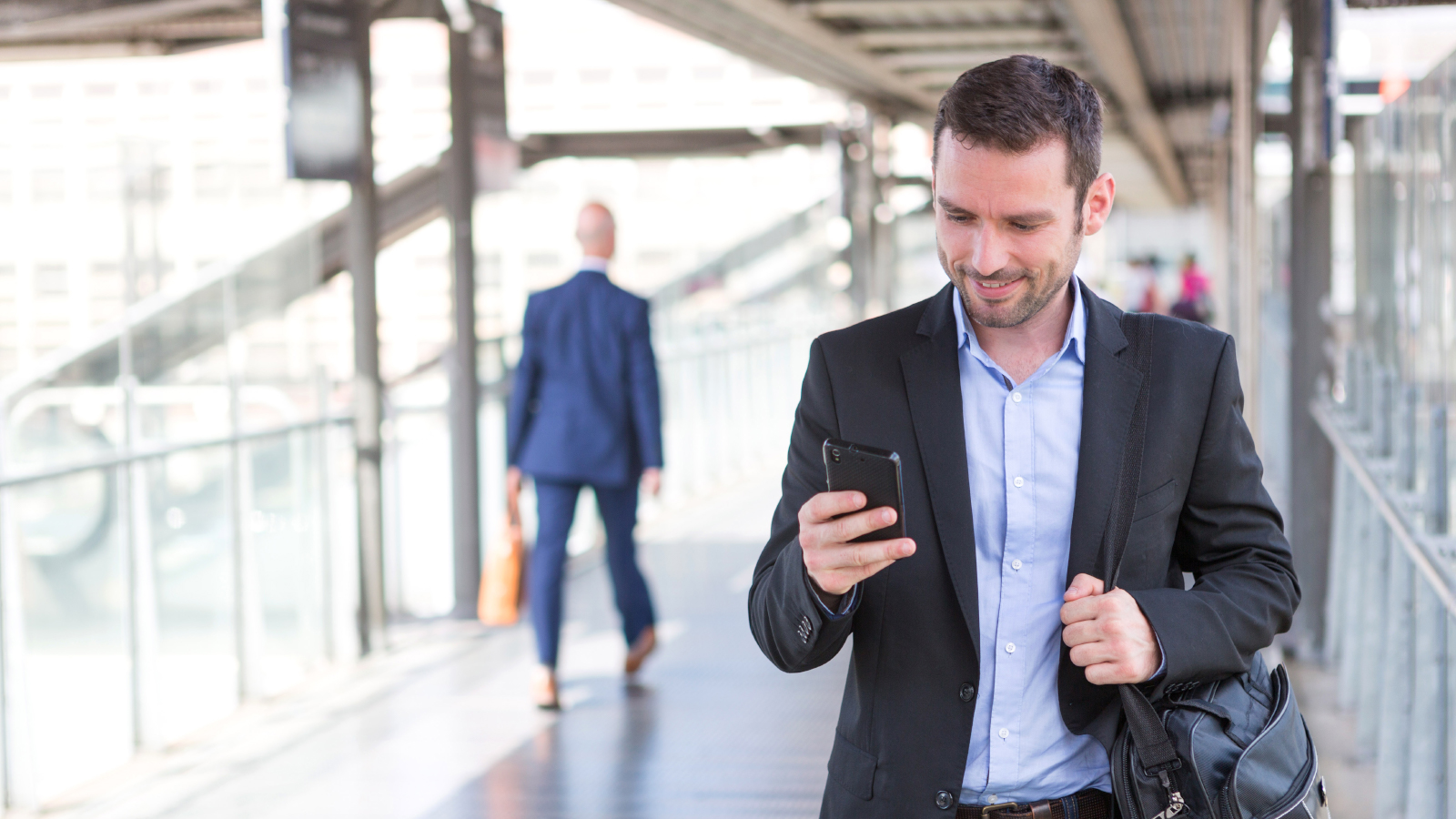 business man walking while looking at mobile phone