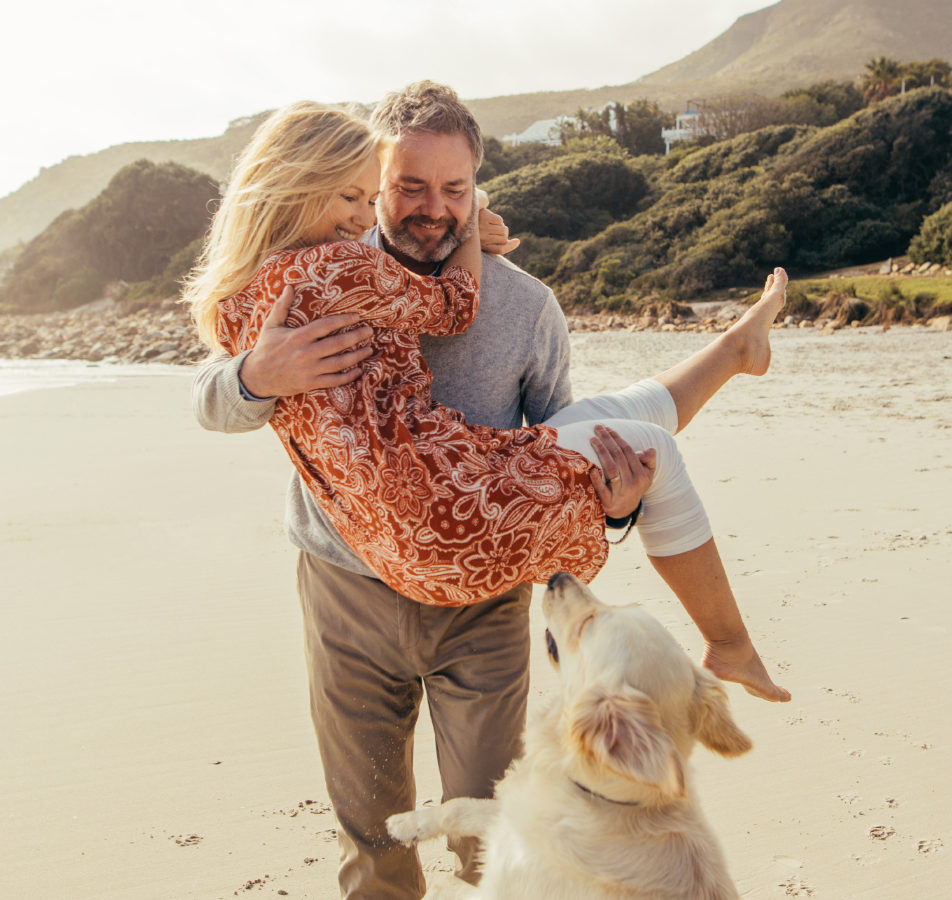 Couple at the beach with their dog.