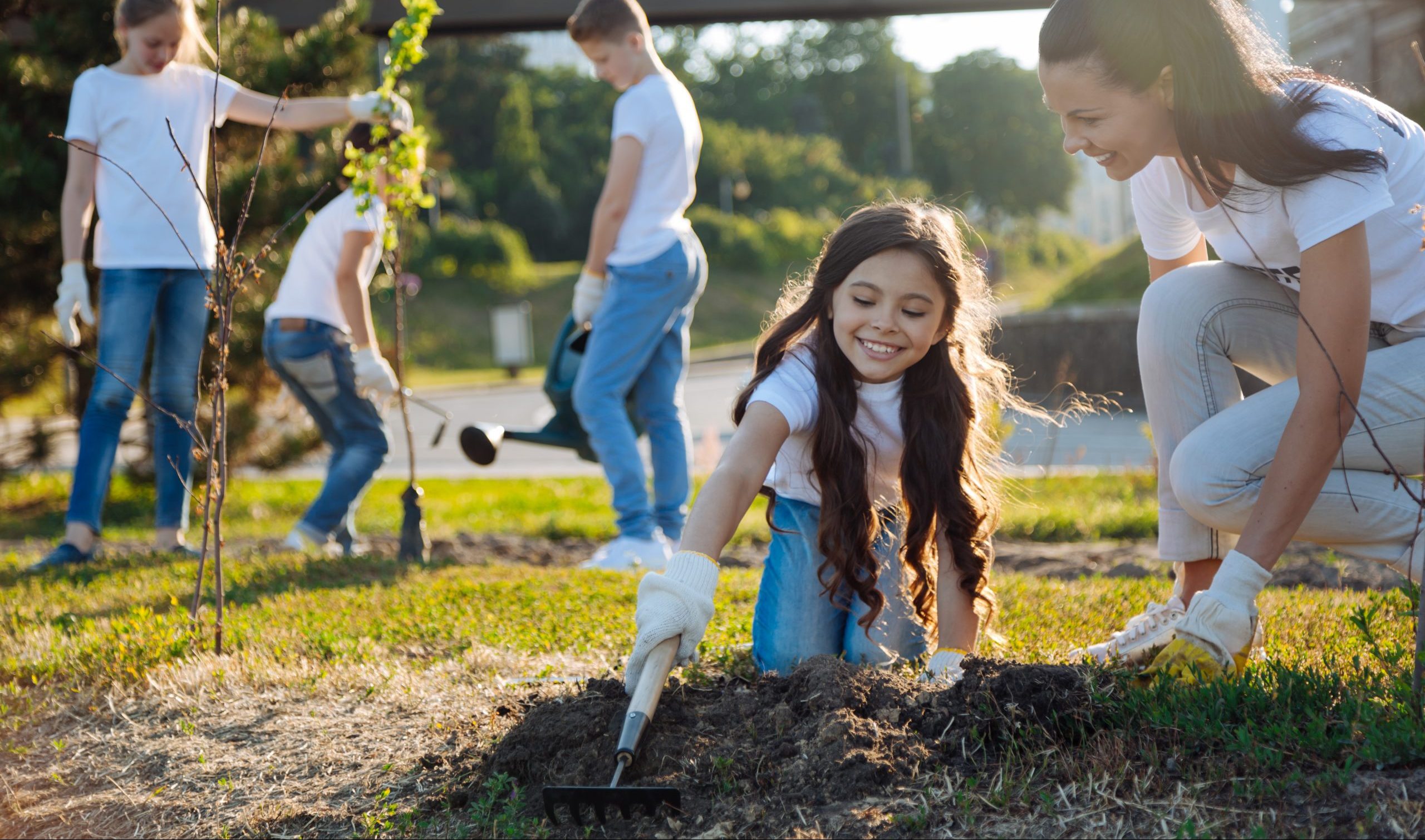 Joyful kids watering new tree